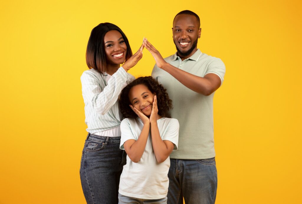 Family care, protection and insurance concept. Young black parents making symbolic roof of hands