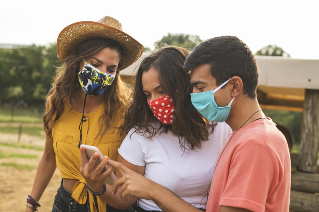 Friends Having Fun Using a Smart Phone in a Ranch with Protective Masks