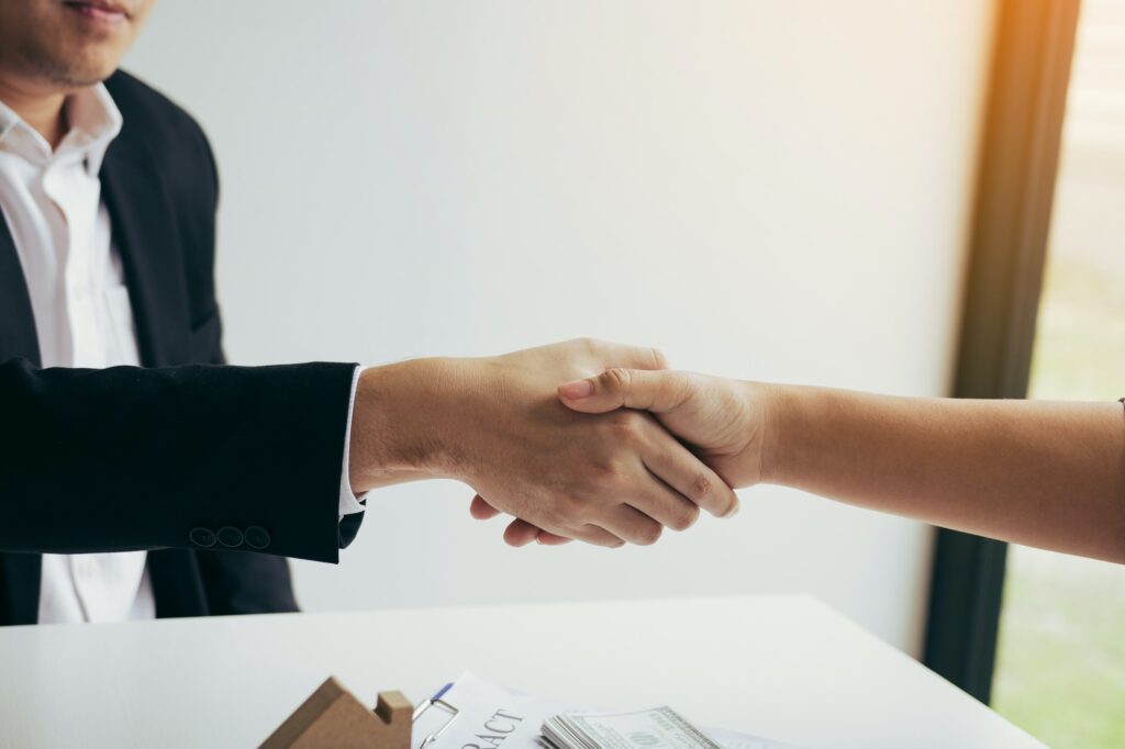 Home sales agents and buyers work on signing new homes and shaking hands.