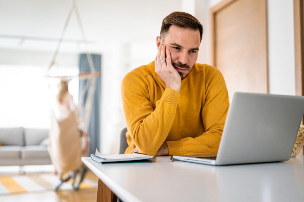 Upset young man counts family budget on laptop